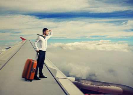 young businessman standing on the wing of an airplaneの写真素材