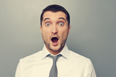 portrait of confused businessman wit open mouth over grey backgroundの写真素材