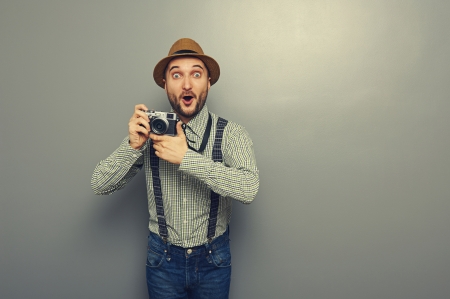 amazed young man with camera over grey background