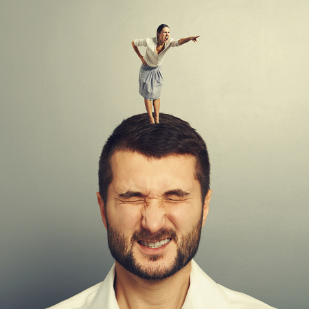 angry screaming woman standing on the head of dissatisfied manの写真素材