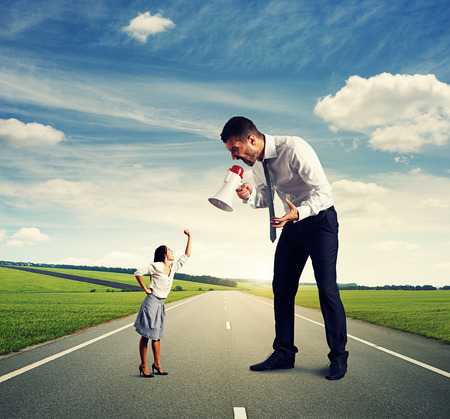 emotional big man with megaphone and small angry woman on the roadの写真素材