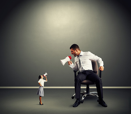 quarrel between small angry woman and big man over dark backgroundの写真素材