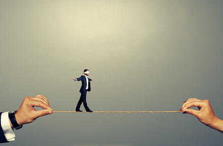 small man walking on the rope over grey backgroundの写真素材