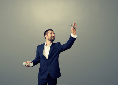 smiley businessman holding paper money over dark backgroundの写真素材