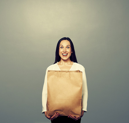 happy girl with paper bag over dark backgroundの写真素材