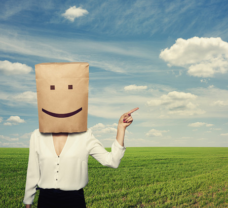 woman with paper bag on the head pointing at something の写真素材