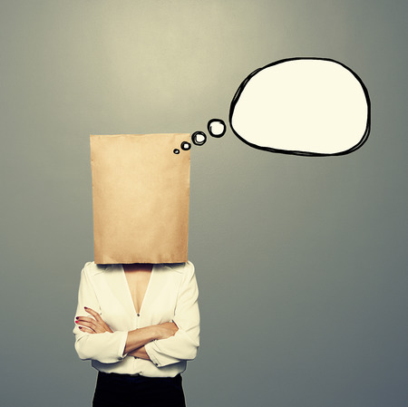 woman with empty paper bag on the head and drawing speech balloon over dark backgroundの写真素材