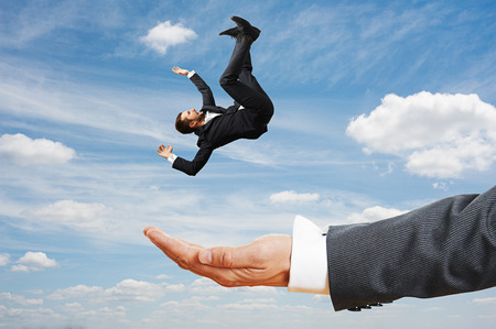big palm catching small frightened businessman over blue skyの写真素材