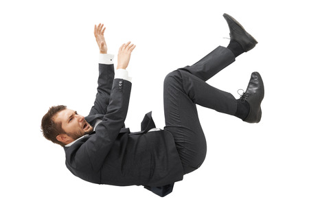 stressed screaming businessman in black suit falling down over white backgroundの写真素材