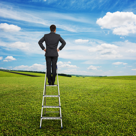 back view of businessman standing on the pair of steps and looking forward at outdoorの写真素材