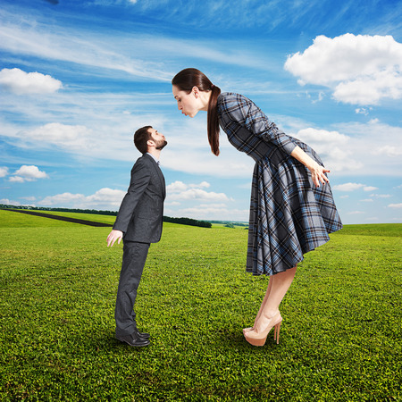 beautiful woman kissing small man. photo at outdoorの写真素材