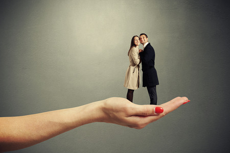 female palm holding small couple in love against dark backgroundの写真素材