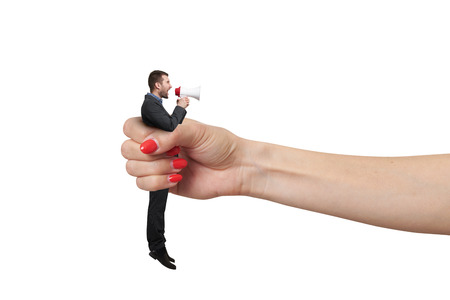 big female hand holding in fist small man and he screaming at megaphone. isolated on white backgroundの写真素材