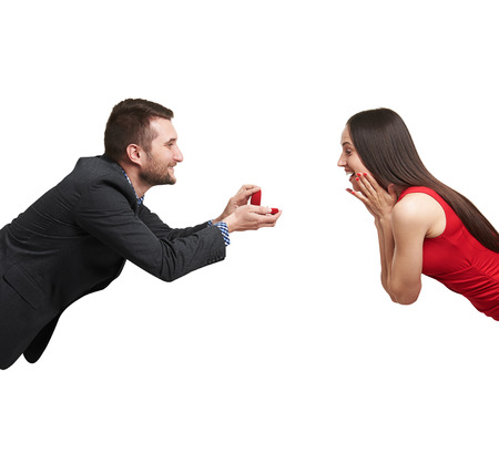amazed happy woman looking at ring and happy man looking at her. isolated on white backgroundの写真素材