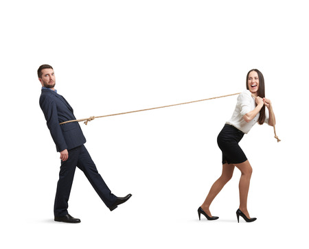 laughing woman pulling man on the rope and looking at him. man following the woman and looking at camera with perplexity. isolated on white backgroundの写真素材