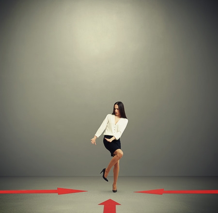 red arrows indicate at frightened woman in formal wear over dark grey background with empty copyspace overheadの写真素材