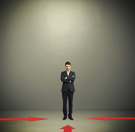 red arrows indicate at pensive businessman in formal wear over dark grey background with empty copyspace overheadの写真素材