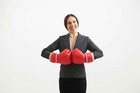 Cheerful businesswoman in red boxing gloves looking at camera over light の写真素材