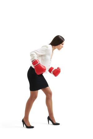 serious businesswoman in formal wear and red gloves standing in boxing pose and looking down over light backgroundの写真素材