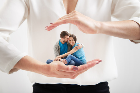 big womanâs hands holding small couple and covering themの写真素材