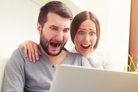 indoor photo of amazed screaming couple looking at laptopの写真素材