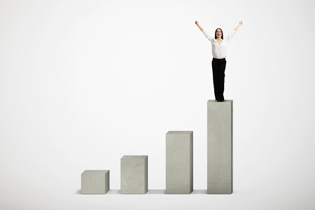 happy woman winner standing on top of concrete diagram over light grey diagramの写真素材