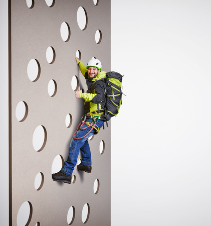 smiley man in equipment holding on climbing wall and showing thumbs up over white backgroundの写真素材