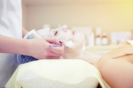 doctor applying cosmetologists mask on womans faceの写真素材
