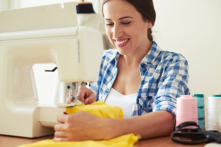 smiley young woman sewing yellow dressの写真素材