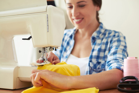 seamstress sewing yellow dress. focus on sewing-machineの写真素材