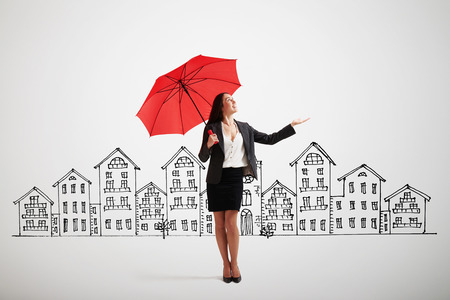 businesswoman with red umbrella held out her hand and looking up over grey background with drawing streetの写真素材