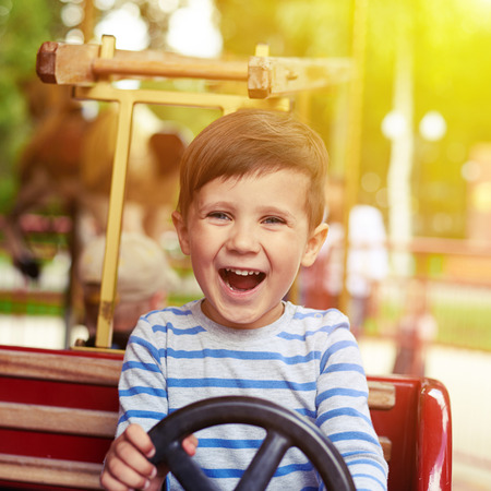 happy little boy driving a car on merry-go-roundの写真素材