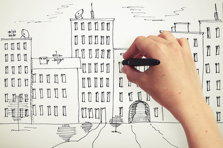 womans hand drawing houses on a paperの写真素材