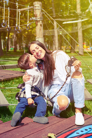 little boy kissing his mother in rope parkの写真素材