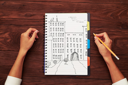 top view of hand-drawn houses on a notepad and pencil in woman hand