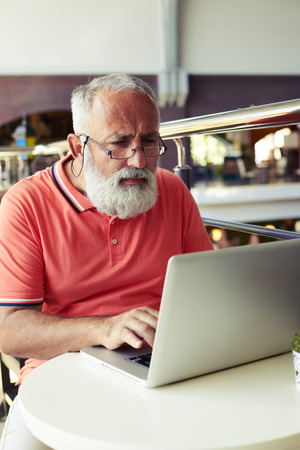 concentrated senior man using laptop in cafeの写真素材