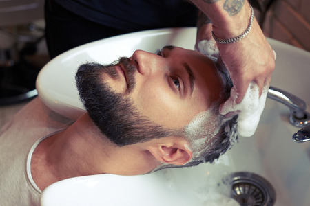 barber washing man head in stylish barbershopの写真素材