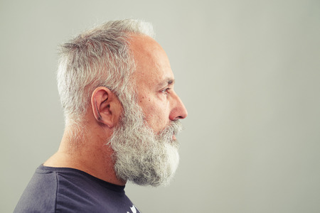 sideview of senior bearded man over light grey background with empty copyspaceの写真素材