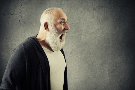 portrait of emotional screaming man with empty copyspace for your text over grey wallの写真素材