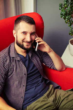 smiley man resting on the chair and talking on the phoneの写真素材