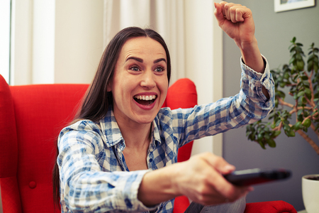 emotional woman watching football on tv at homeの写真素材