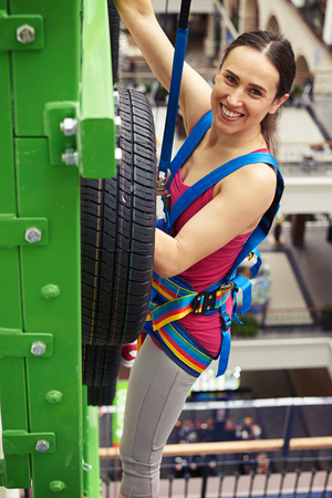 Sportswoman in safety equipment is climbing on the wall in indoor rock-climbing sport centerの写真素材