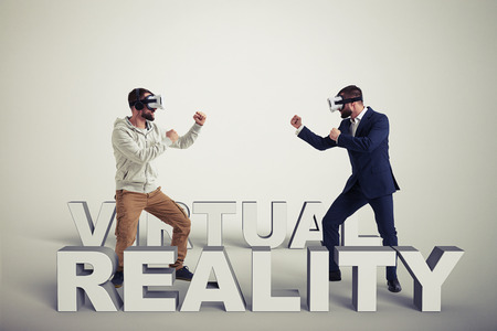 Two men, one in casual clothes, another in dark business suit, are wearing virtual reality glasses...