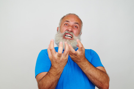 Aged bearded man is grimacing at the camera expressing extreme nervousness isolated on white backgroundの写真素材