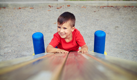 Curious active boy with blue eyes climbing up at the playground on a bright sunny dayの写真素材