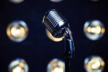 Close-up shot of retro silver microphone on spotlights blurred background. Microphone isolated on white background. Classical vintage standing microphoneの写真素材