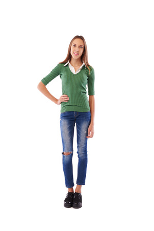 Full-length shot of slim teenage holding one hand on hip while posing at the camera in studio over white backgroundの写真素材