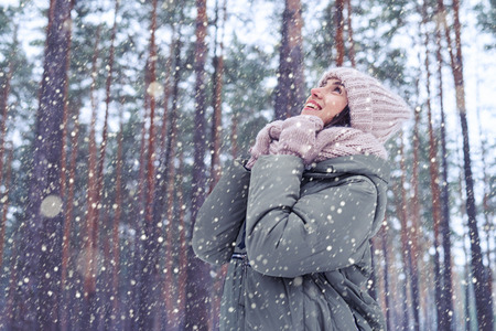 Low angle of thoughtful attractive trendy woman in stylish winter fashion clothes making a wish....