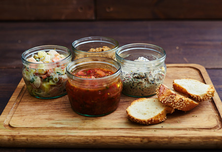 Close-up of a mix of homemade salads in jars served with crusty bread. Dressed salad for lunch....