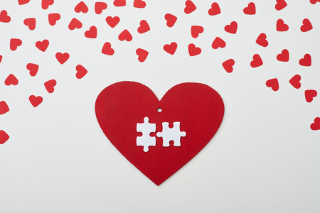 Top view of two puzzle pieces on carton red card. Red heart surrounded by small hearts.の写真素材
